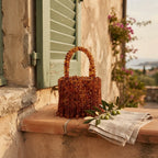 Brown beaded fringe clutch bag styled in a warm Mediterranean setting