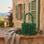 Green beaded fringe clutch bag styled in a warm Mediterranean setting