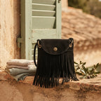 Black black fringe messenger bag styled in a warm Mediterranean setting