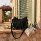 Black black suede fringe hobo bag styled in a warm Mediterranean setting