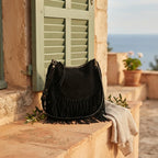 Black bohemian fringe bag styled in a warm Mediterranean setting