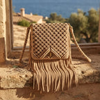 Beige boho fringe shoulder bag styled in a warm Mediterranean setting