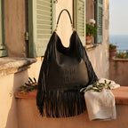 Black boho leather fringe bag styled in a warm Mediterranean setting