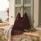 Maroon boho leather fringe bag styled in a warm Mediterranean setting