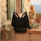 Black boho style fringe bag styled in a warm Mediterranean setting