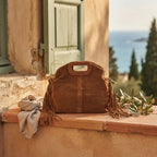 Brown brown suede fringe shoulder bag styled in a warm Mediterranean setting