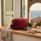 Red burgundy fringe bag styled in a warm Mediterranean setting