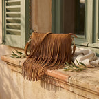 Brown camel fringe crossbody bag styled in a warm Mediterranean setting