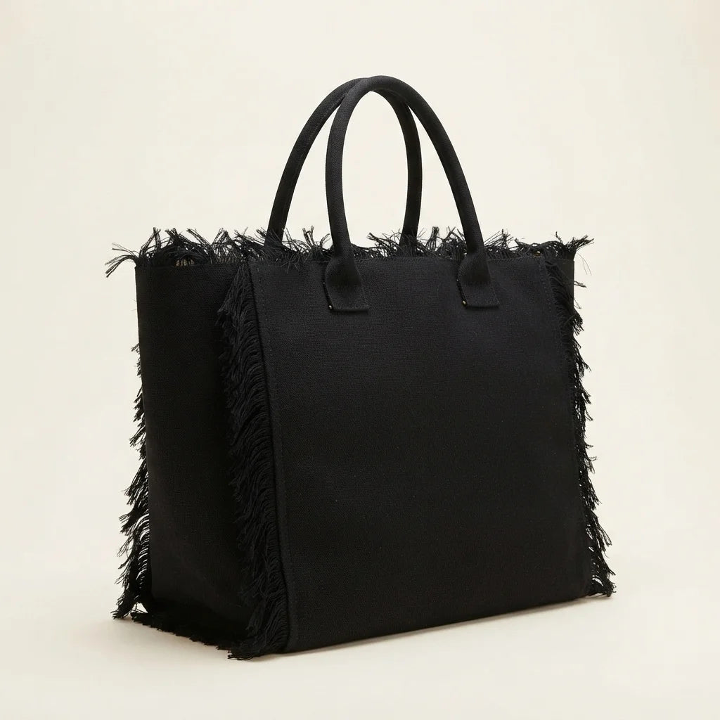 Black canvas fringe tote bag, three-quarter angle showing side depth