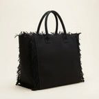 Black canvas fringe tote bag, three-quarter angle showing side depth