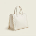 White canvas fringe tote bag, three-quarter angle showing side depth