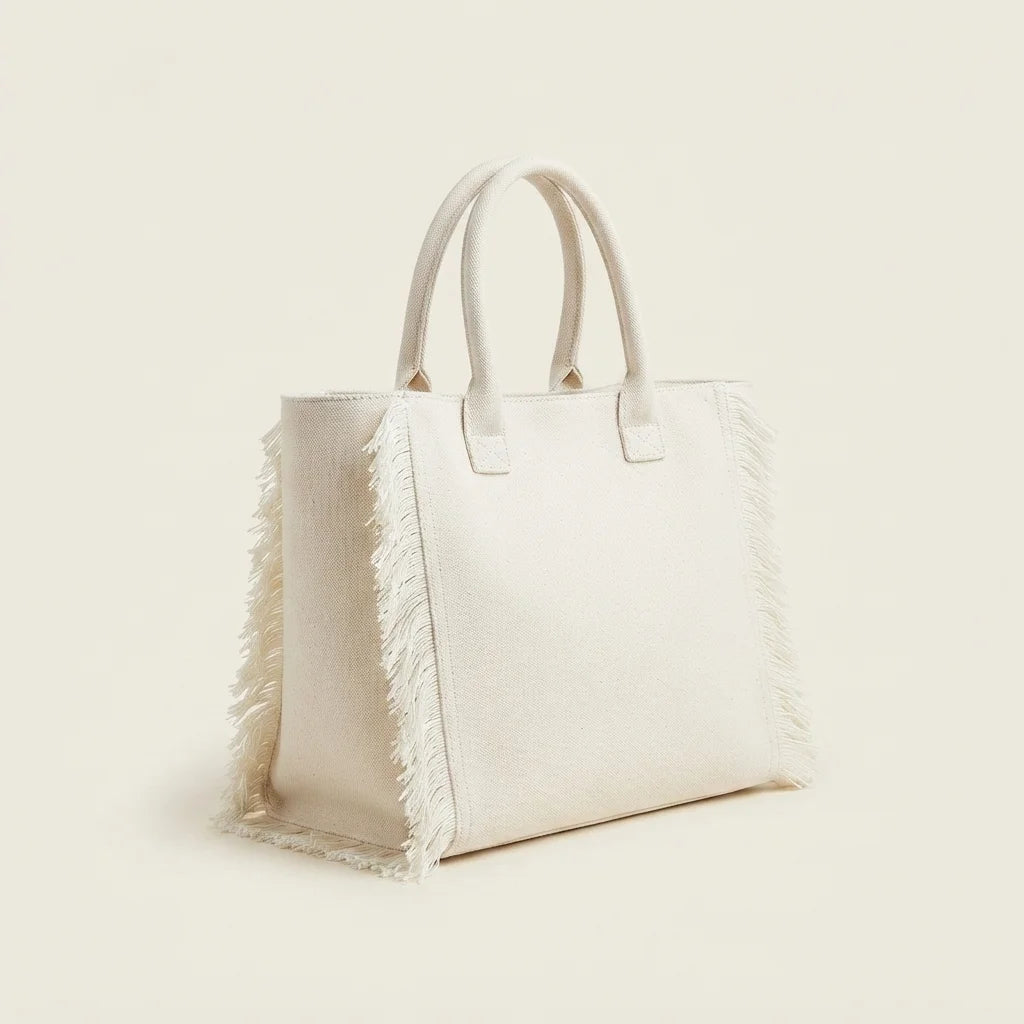 White canvas fringe tote bag, three-quarter angle showing side depth