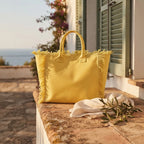 Yellow canvas fringe tote bag styled in a warm Mediterranean setting