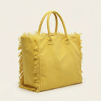 Yellow canvas fringe tote bag, three-quarter angle showing side depth