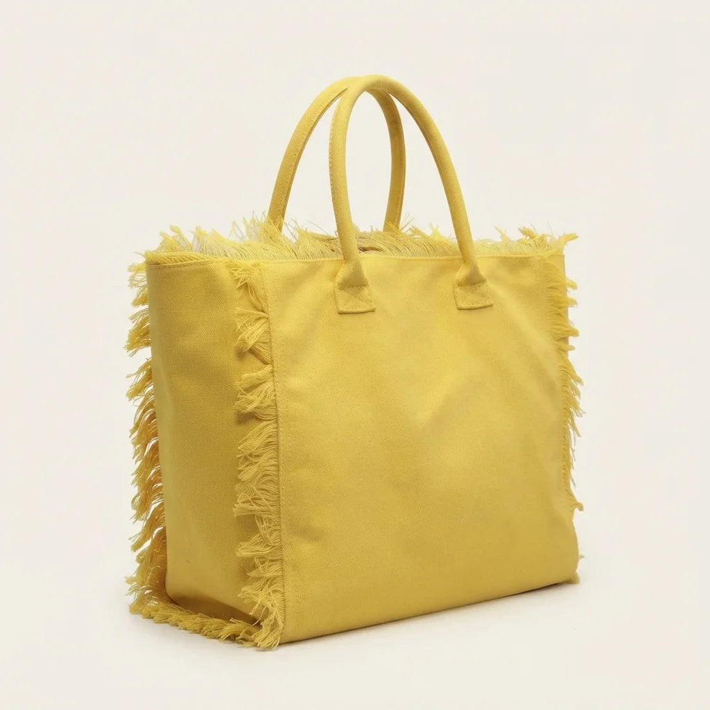 Yellow canvas fringe tote bag, three-quarter angle showing side depth