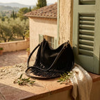 Black cowhide bag with fringe styled in a warm Mediterranean setting