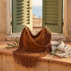 Brown cowhide bag with fringe styled in a warm Mediterranean setting