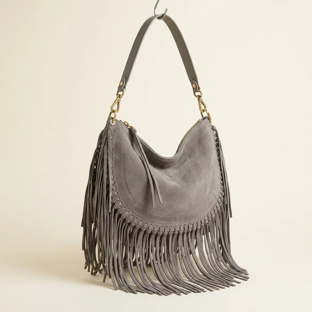 Grey cowhide bag with fringe, three-quarter angle showing side depth