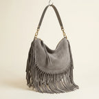 Grey cowhide bag with fringe, three-quarter angle showing side depth