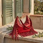 Wine Red faux leather fringe hobo bag styled in a warm Mediterranean setting