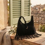 Black faux suede fringe bag styled in a warm Mediterranean setting