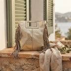 Gold fringe backpack shoulder bag styled in a warm Mediterranean setting