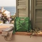 Green fringe backpack shoulder bag styled in a warm Mediterranean setting
