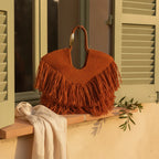 Orange fringe beach bag styled in a warm Mediterranean setting