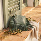 Green fringe clutch bag leather styled in a warm Mediterranean setting