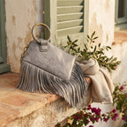 Grey fringe clutch bag leather styled in a warm Mediterranean setting