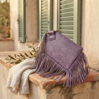 Purple fringe clutch bag leather styled in a warm Mediterranean setting