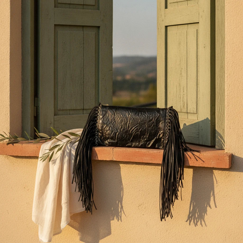 Black fringe clutch crossbody bag styled in a warm Mediterranean setting