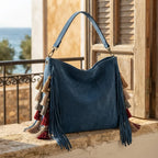 Blue fringe hobo shoulder bags styled in a warm Mediterranean setting