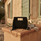 Black fringe satchel bag styled in a warm Mediterranean setting