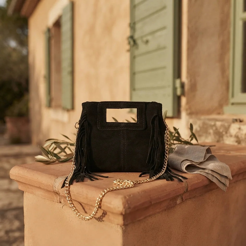 Black fringe satchel bag styled in a warm Mediterranean setting