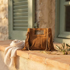 Camel fringe satchel bag styled in a warm Mediterranean setting