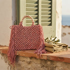 Pink fringe shoulder bag with tassels styled in a warm Mediterranean setting