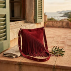 Red fringe suede belt bag styled in a warm Mediterranean setting
