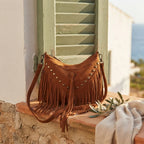 Brown fringe tassel crossbody bag styled in a warm Mediterranean setting