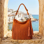 Orange fringe tassel shoulder bag styled in a warm Mediterranean setting
