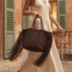 Woman wearing Natural fringed straw tote bag with swaying fringe
