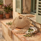 Beige large macrame fringed tote bag styled in a warm Mediterranean setting