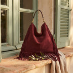 Maroon large suede fringe bag styled in a warm Mediterranean setting