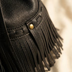 Close-up of fringe stitching and texture on Black leather bucket bag with fringes
