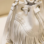 Close-up of fringe stitching and texture on White leather bucket bag with fringes