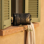 Black leather clutch bags with side fringe styled in a warm Mediterranean setting