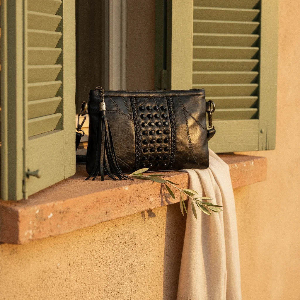 Black leather clutch bags with side fringe styled in a warm Mediterranean setting