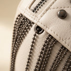 Close-up of fringe stitching and texture on Beige leather fringe belt bag
