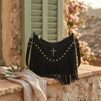 Black leather fringe messenger bag styled in a warm Mediterranean setting