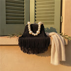 Black long fringe clutch bag styled in a warm Mediterranean setting